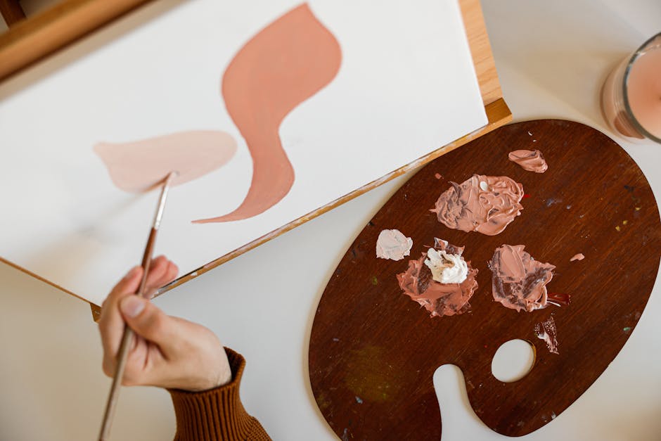 Close-up of an artist's hand painting abstract shapes with a palette on canvas.